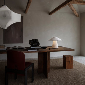 Modern interior with wooden desk, chair, and lamp in a room with exposed beams.