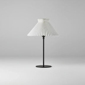 Table lamp with pleated white shade on a gray background