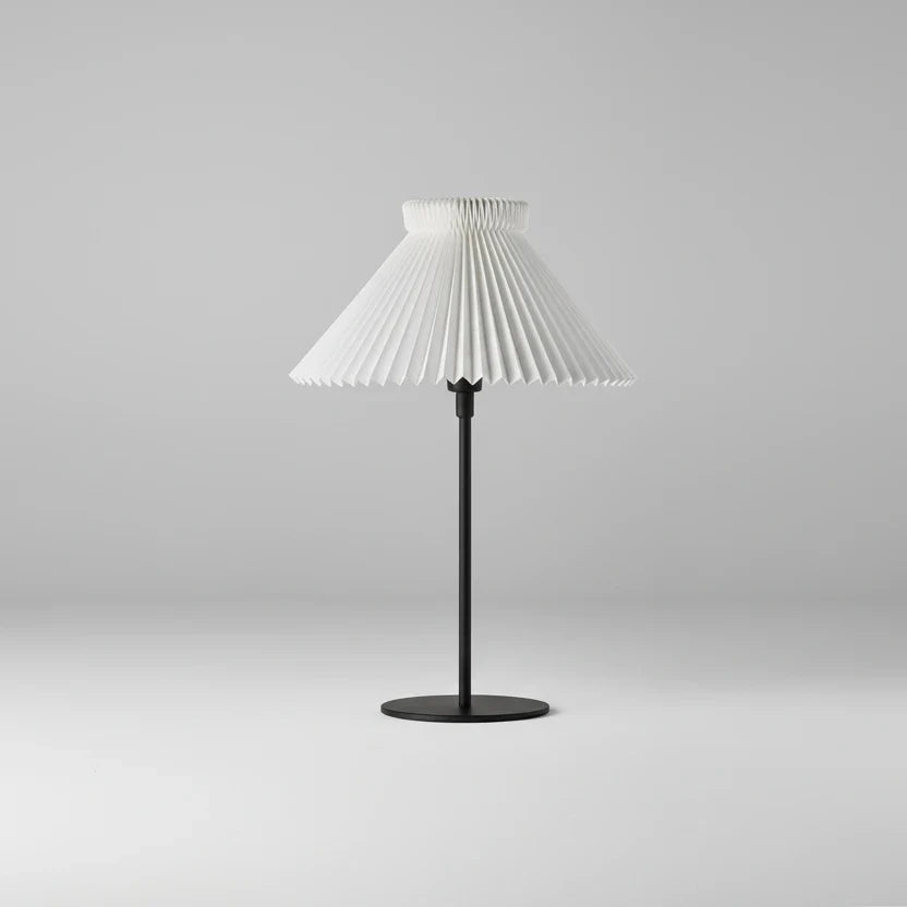 Table lamp with pleated white shade on a gray background